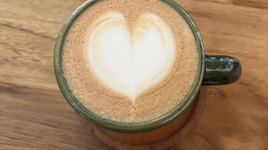 A coffee with a latte art heart in a green cup at Artisan in Uluwatu